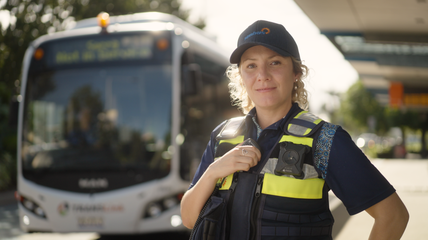 A security officer poses in front of a bus for a video