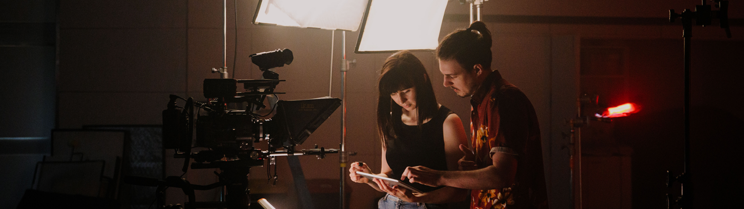 A producer and director read a script on a video production set.