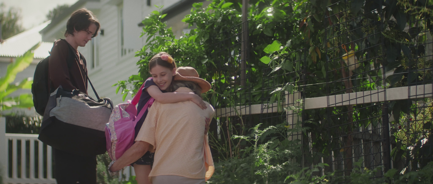 Grandma hugs her grand daughter as her brother looks on. 